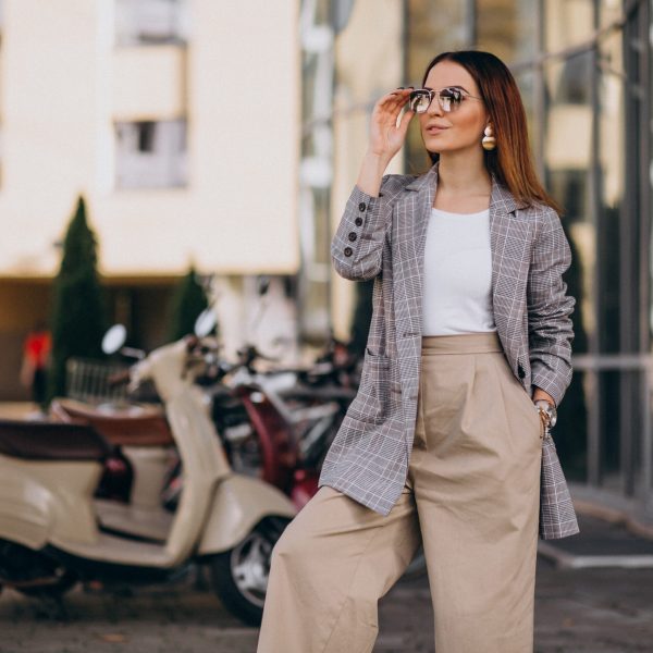 Young woman in suit standing by the scooter